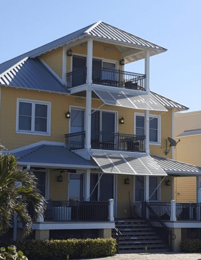 A yellow house with balconies and palm trees.