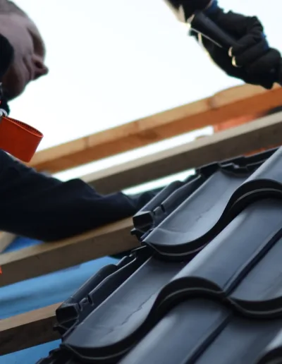 A man is working on a tile roof.