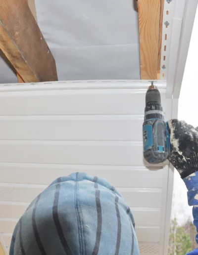 A man using a drill on a roof.