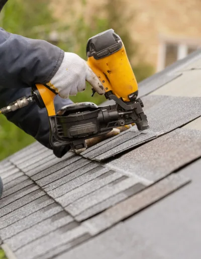 A man is working on a shingled roof.