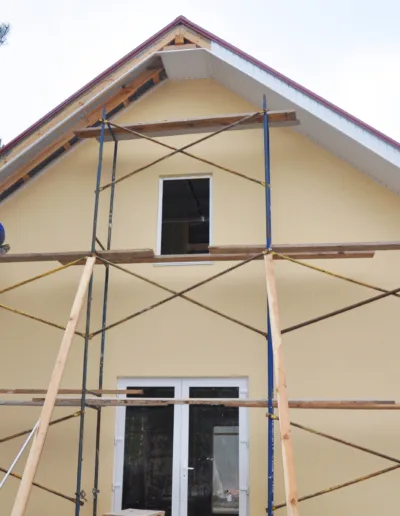 A man is working on a house with scaffolding.